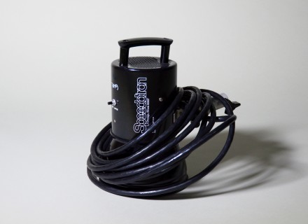 Photograph of Speedotron Light Head with cable wrapped around it and presented on a grey background.