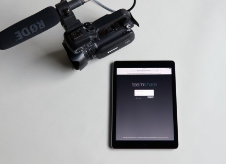 Photography of a Canon XA10 camcorder alongside an iPad with the Team Share login on its screen.