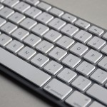 Close up photograph of Apple white and silver keyboard on a grey backdrop.