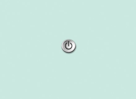 Photo of a round power button sitting on a turquoise background.